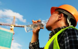 A worker avoiding summer heat stress by drinking water.