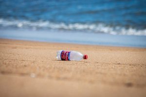 A photo of a plastic bottle on the beach.
