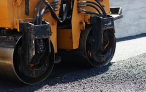A photo showing a road roller compacting sealcoating.